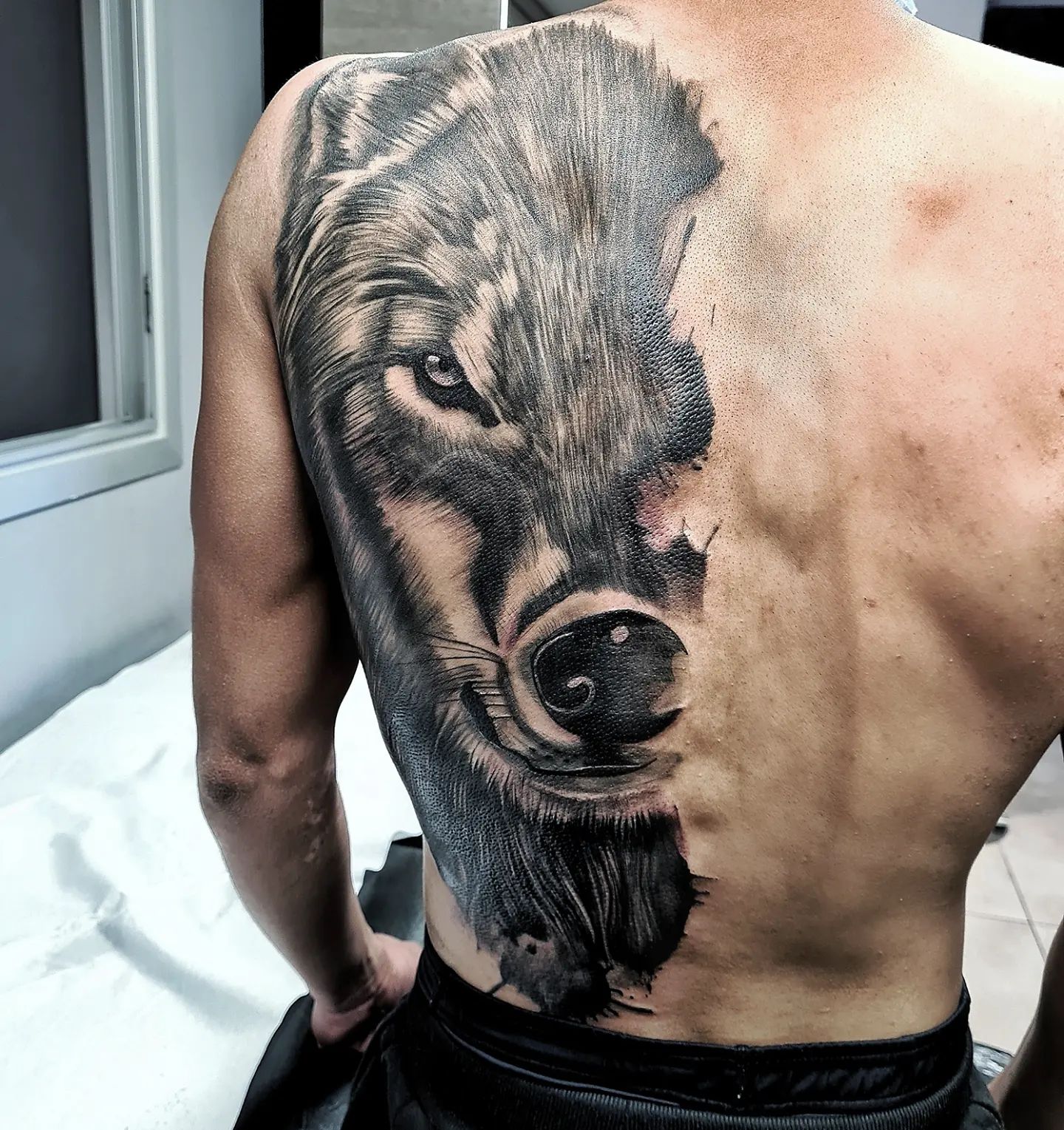 Tatuaje de lobo de media cara en la espalda.